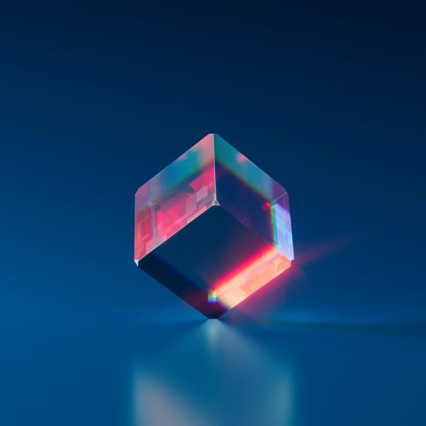 Imagem de um cubo transparente com reflexos vermelhos e equilibrado sobre um dos vertices